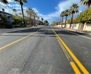 Reconstructed roadway bright yellow striping with palm trees on side of road