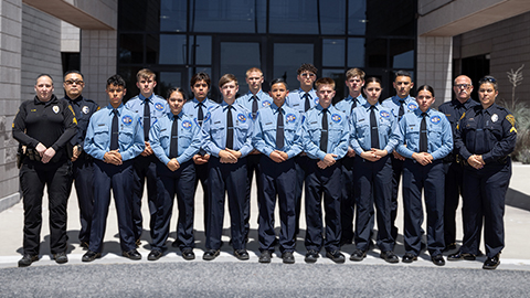 Class photo of Explorers and some TPD advisors in uniform in front of a desaturated background.